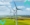 An image of a land-based wind farm in the countryside with blue skies and sunshine