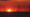 An image of a wind farm out at sea with a red sunset behind it