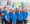 A group of male and female Pepco employees stand in a group in a shop, smiling at the camera